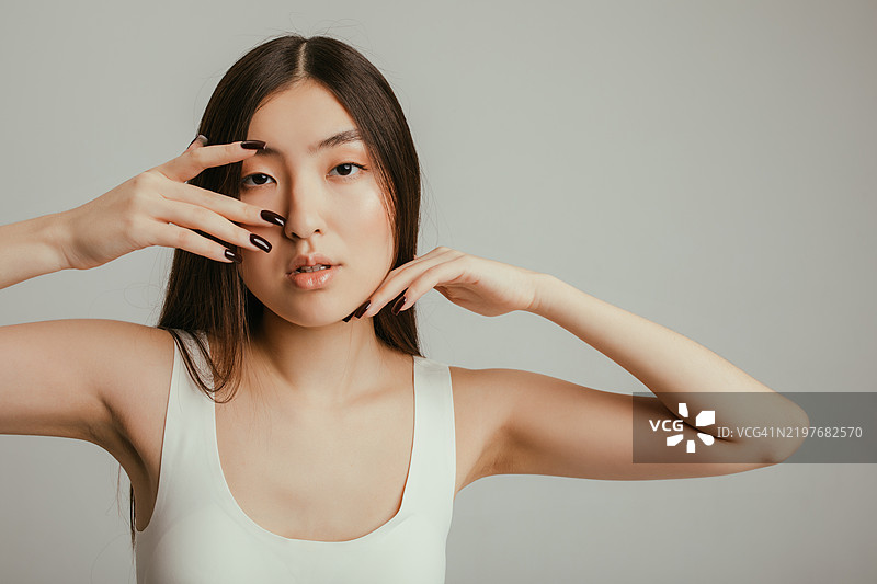 美丽的亚洲女性摆出手势，指甲修饰精致，背景简约图片素材