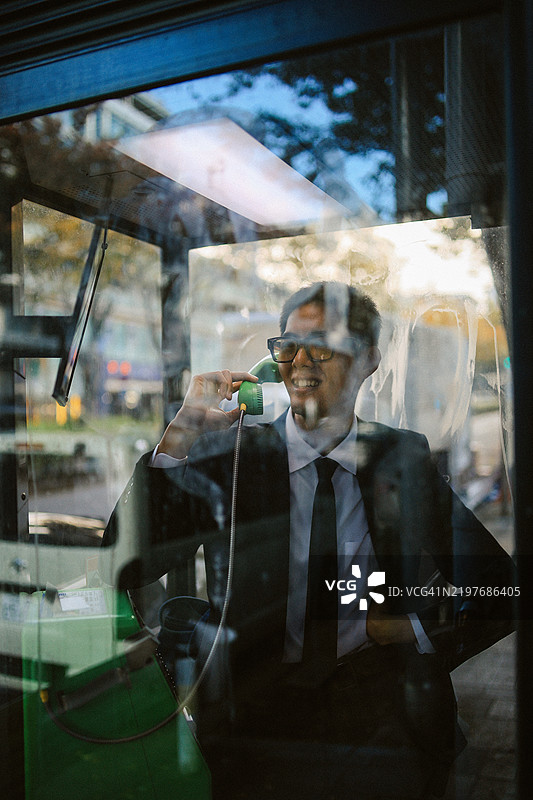 在东京的公用电话亭里打电话的男人图片素材