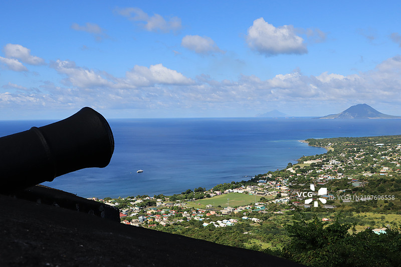 从圣基茨岛的布林斯通山堡国家公园俯瞰沙迪角镇，前景中有轮廓分明的炮管。图片素材