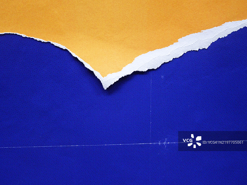 蓝色背景与撕裂的黄色纸张图片素材