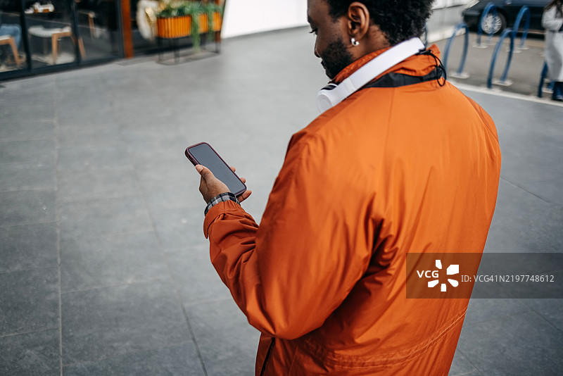 黑人在户外使用手机，屏幕为空白图片素材