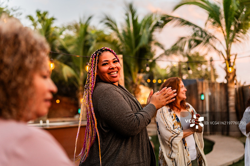 中年女性在灵修静修期间与朋友们围绕篝火欢呼和唱歌的肖像图片素材