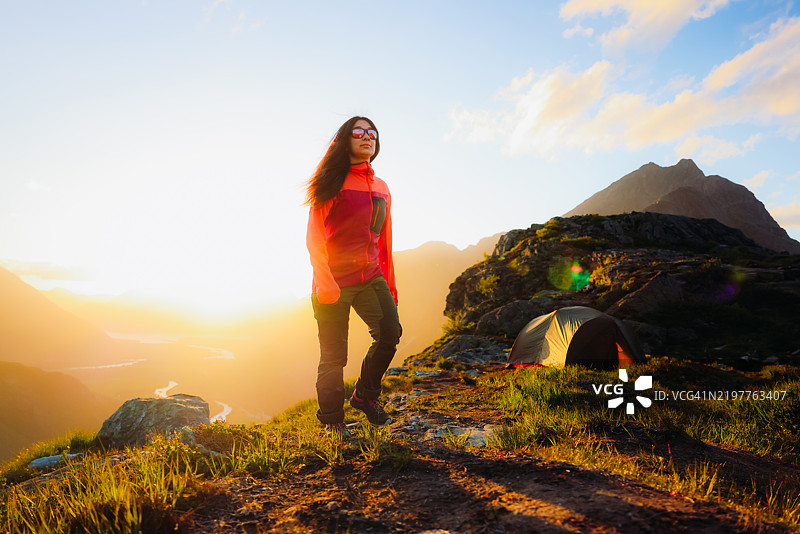 自信的女性在山中露营，欣赏日落时美丽的山谷景色图片素材