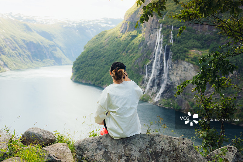 女人沉思于宁静的北欧风景，俯瞰瀑布和盖朗厄尔峡湾图片素材