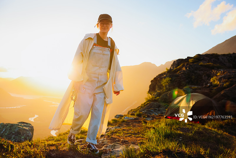 女性登山者在山中露营，欣赏日落时分的美丽山谷景色图片素材