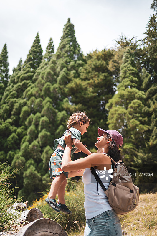 母亲在风景如画的森林中抱起她的孩子图片素材