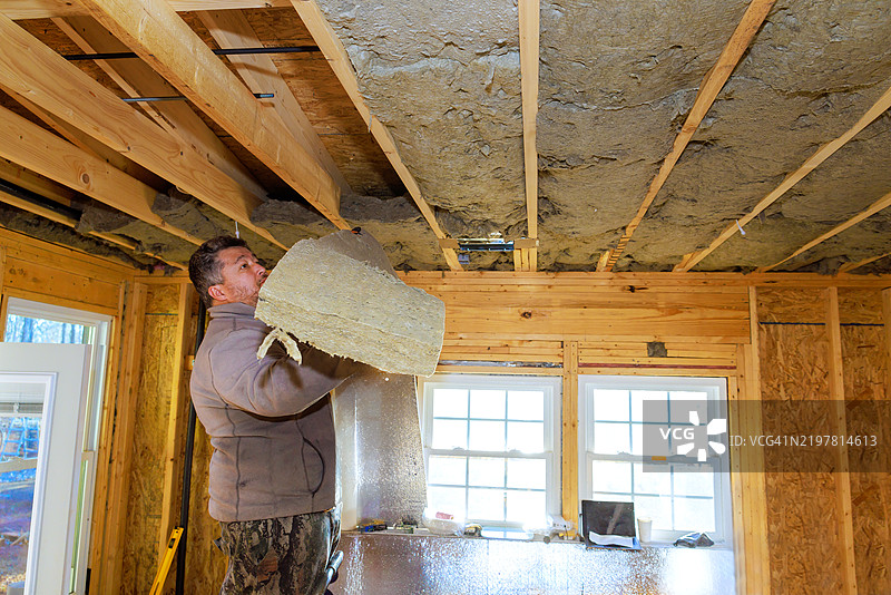 男子在阳光明媚的家庭装修项目中安装绝缘材料图片素材