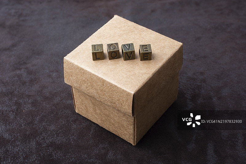 金属字母拼成的“爱”字放在盒子上，象征着爱的概念图片素材