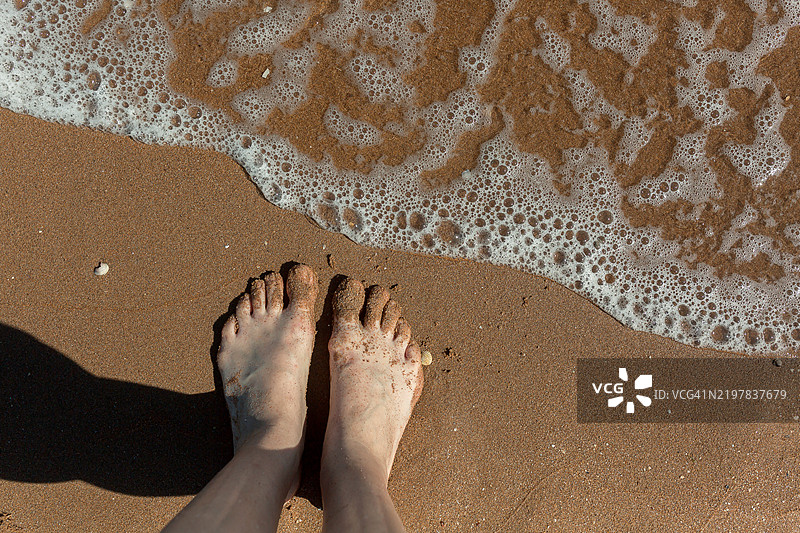 赤脚踩在沙滩上。图片素材