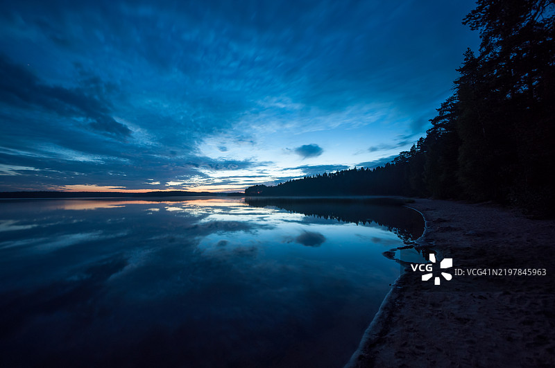 平静湖面上反射出的蓝色傍晚色彩，皮尔卡南，芬兰图片素材