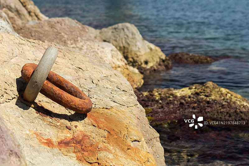 生锈的钩子用来将船锁定在岩石海岸上图片素材