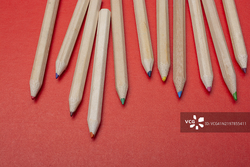红色背景上的彩色铅笔。许多不同颜色的铅笔。图片素材