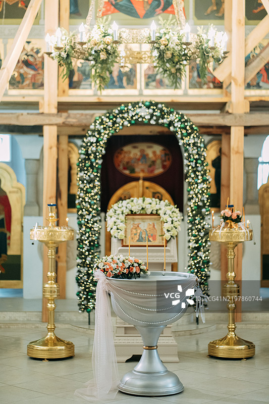 装饰着花朵的银色洗礼盆矗立在教堂内部图片素材