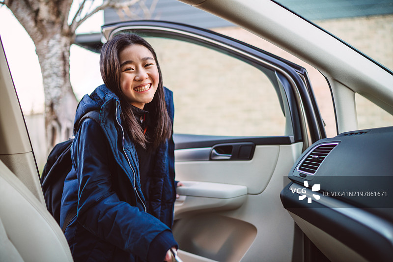 快乐的女学生在寒冷的早晨上车图片素材