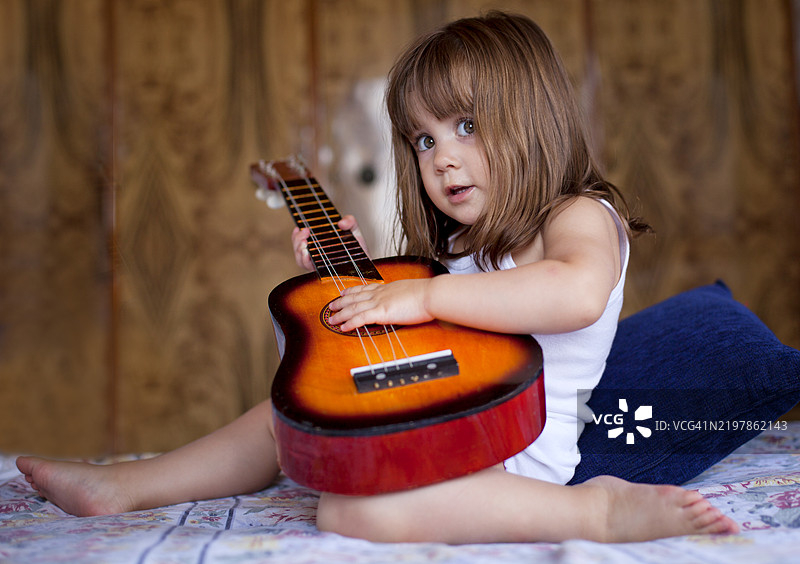 年轻孩子在舒适的室内环境中弹吉他图片素材