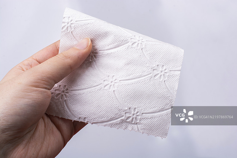 一只女性的手拿起一张白色卫生纸。图片素材