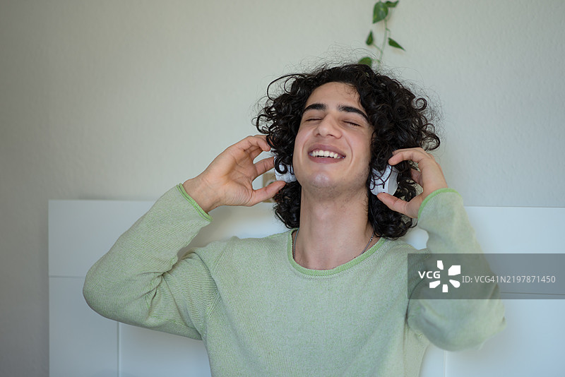 年轻男子戴着无线耳机享受音乐。图片素材