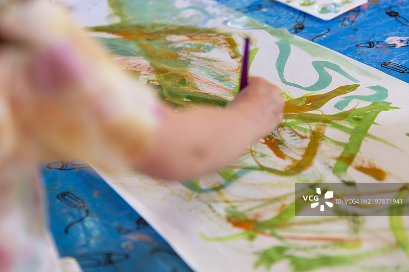 四岁小孩用绿色、橙色和蓝色颜料绘画的背影镜头图片素材