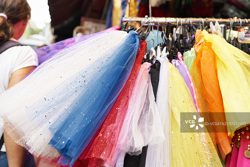 美丽明亮的芭蕾舞裙挂在跳蚤市场的女孩服装店柜台上。图片素材