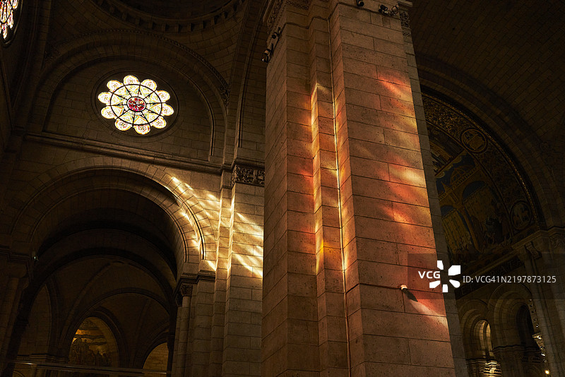 阳光透过彩色玻璃窗洒入天主教教堂，墙壁上映出美丽的色彩。图片素材