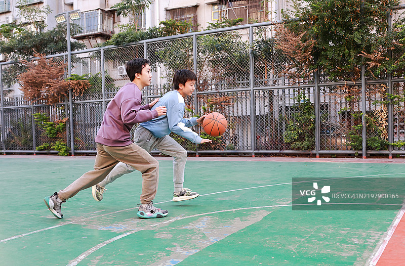 两个年轻男孩在公园里打篮球图片素材