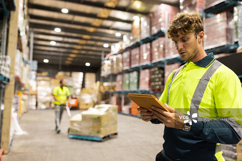 仓库工人使用数字技术进行物流和库存管理图片素材