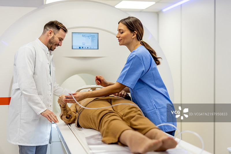 医生和护士协助患者进行现代医学影像检查图片素材