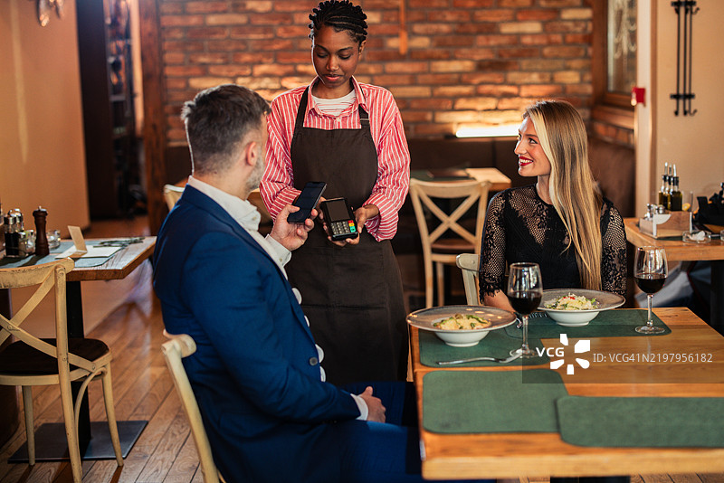 男人与妻子共进晚餐，向女服务员付款图片素材