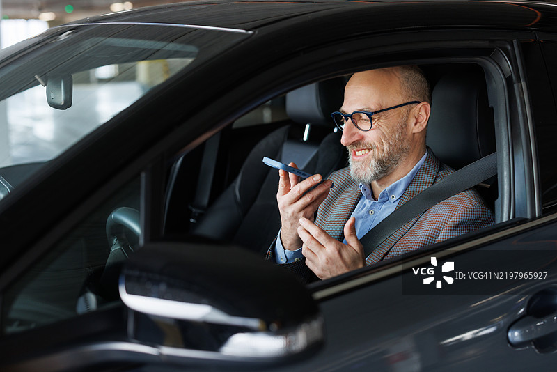 一位现代男性在车内通过扬声器进行电话交谈图片素材