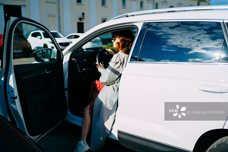 阳光明媚的日子里，女人驾驶着白色汽车图片素材