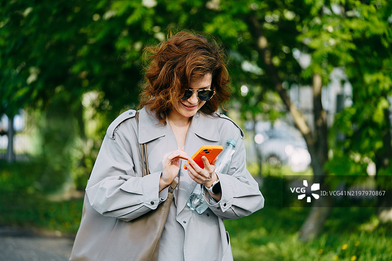 女性在公园环境中使用智能手机图片素材
