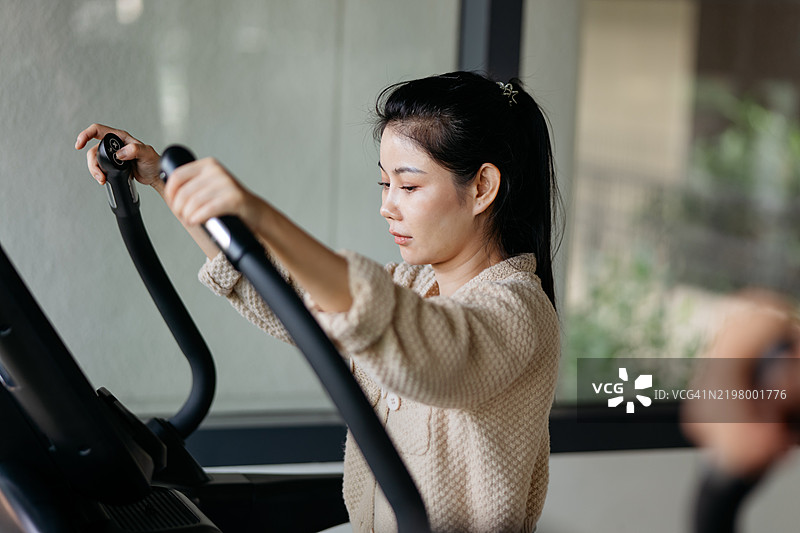 亚洲女性在跑步机上跑步图片素材
