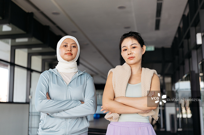 健身工作室中，两位亚洲女性在锻炼后微笑着看向镜头的半身肖像图片素材
