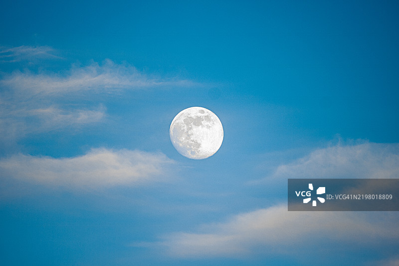蓝天中被云彩环绕的月亮图片素材