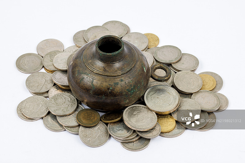 白色背景上的青铜油灯，周围环绕着来自弗朗哥独裁时期的西班牙硬币图片素材