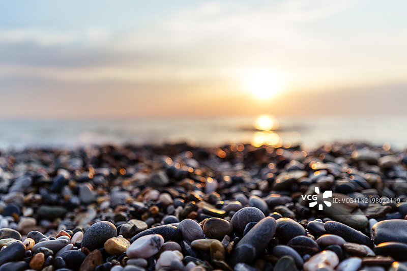 迷人的海洋日落景观与卵石海滩图片素材