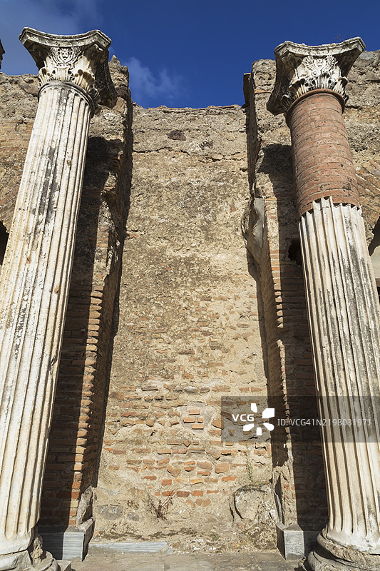 古老的陶土砖和石墙遗迹从大理石柱子中低角度呈现，柱子上雕刻着细致的图案，位于意大利坎帕尼亚地区的庞贝古遗址。图片素材