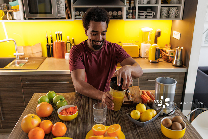 男子在明亮现代的厨房环境中准备新鲜的柑橘汁图片素材