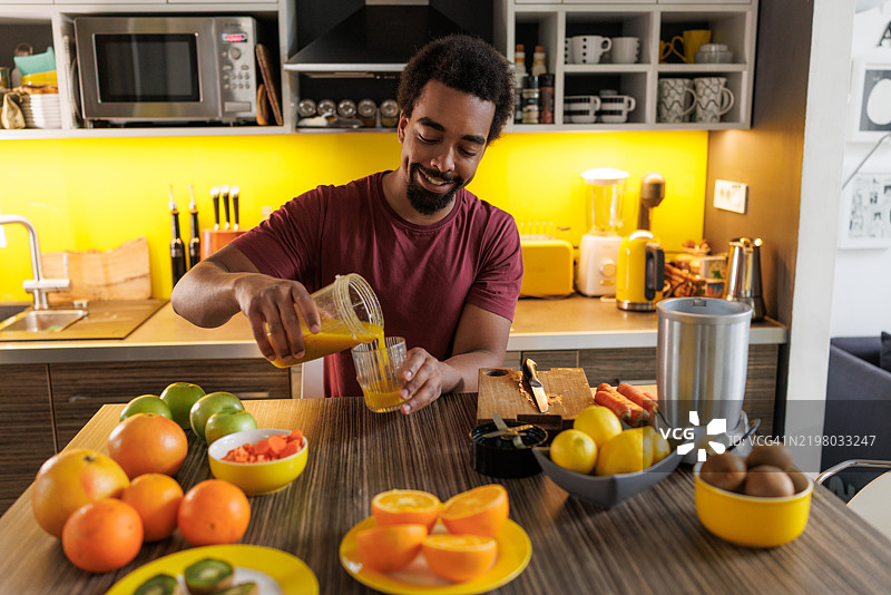 男子在现代厨房环境中准备新鲜果汁图片素材