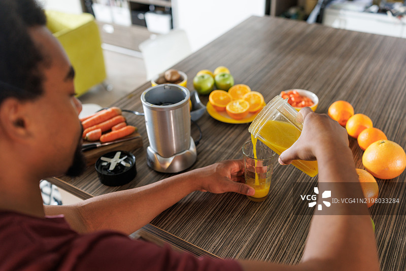 男子在厨房台面上用有机食材准备新鲜果汁图片素材