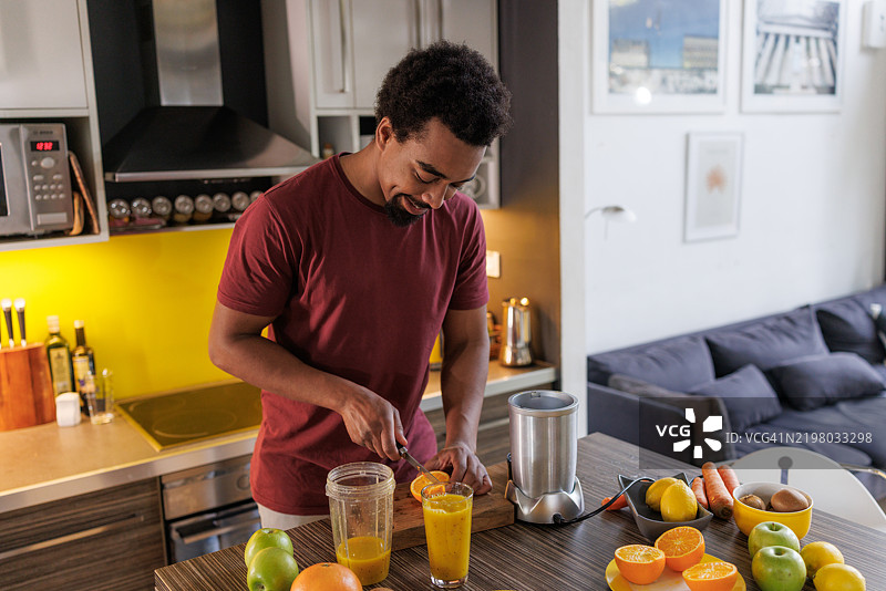 男人在家里的厨房里制作新鲜果汁图片素材