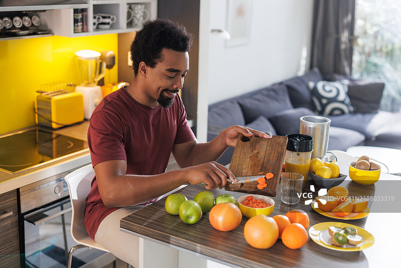 男子在厨房准备健康的水果冰沙，作为营养餐。图片素材