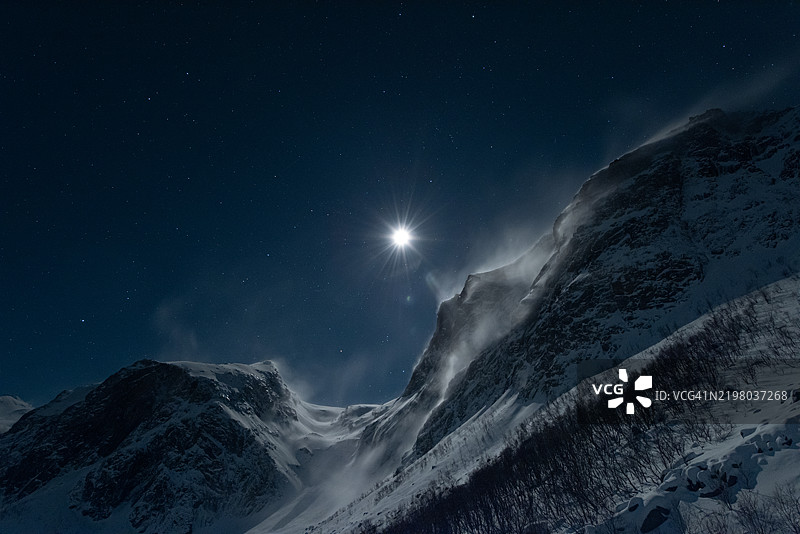 格罗特峡湾上空的满月照耀着被雪覆盖且多风的山脉图片素材