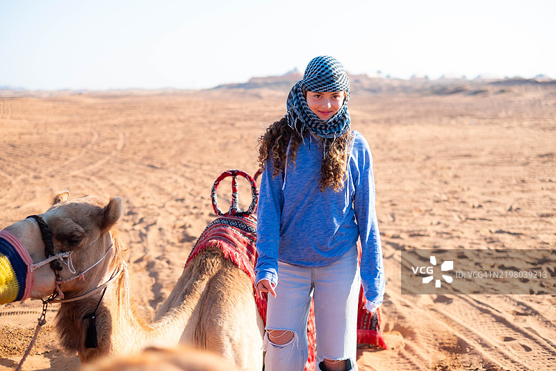 一个少女在沙漠中与骆驼一起参加野生动物探险。图片素材