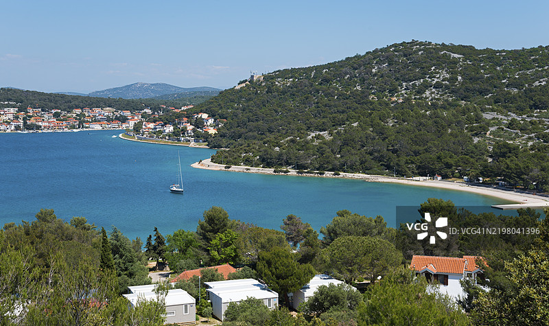 沿海小镇，松树和帆船环绕，蓝色海洋和海湾，靠近克罗地亚希贝尼克-克宁的蒂斯诺。图片素材
