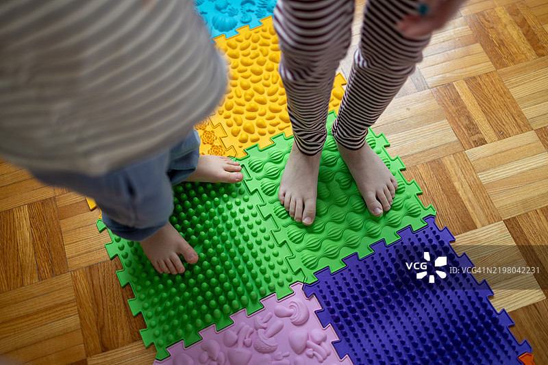 孩子们赤脚站在按摩垫上。图片素材