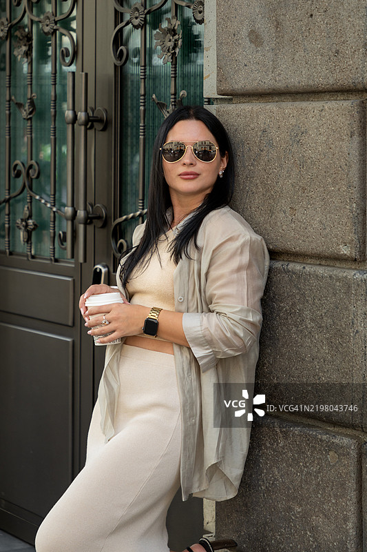 时尚的年轻女性在户外享受咖啡休息时间图片素材