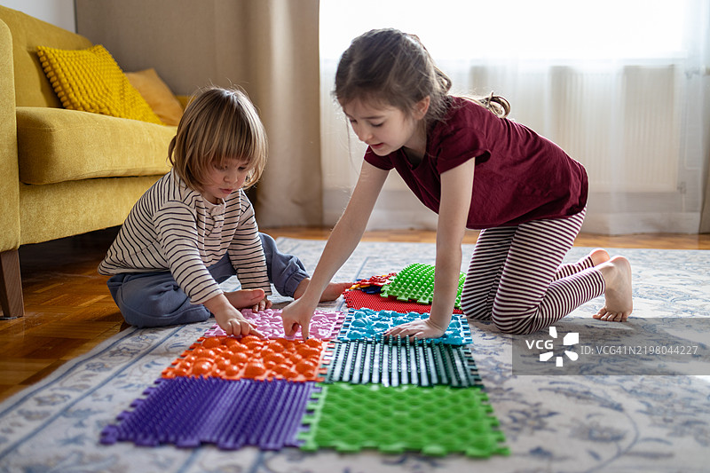 孩子们在木地板上搭建按摩垫。预防家庭扁平足图片素材