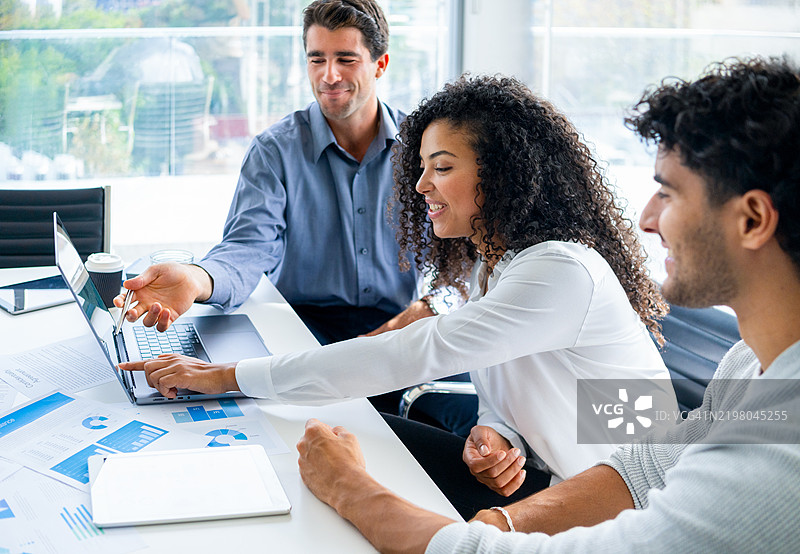 三个人正在查看和讨论带有图表和图形的财务数据图片素材