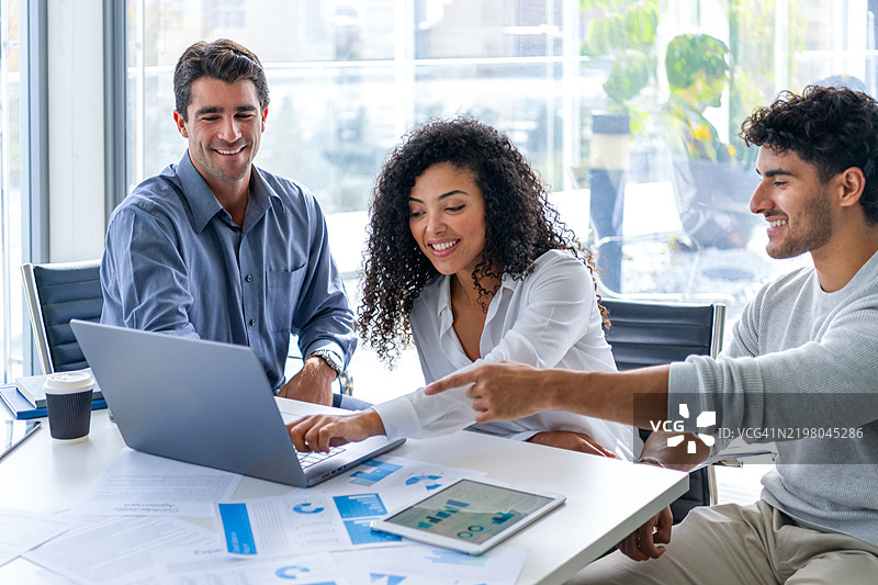 三个人正在查看并讨论带有图表和图形的财务数据。图片素材